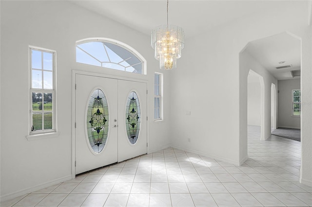 tiled foyer featuring a towering ceiling and a chandelier