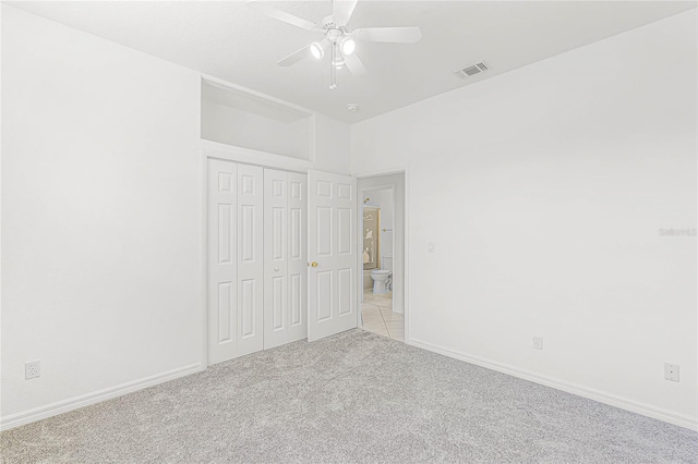 unfurnished bedroom with ceiling fan, light colored carpet, and a closet