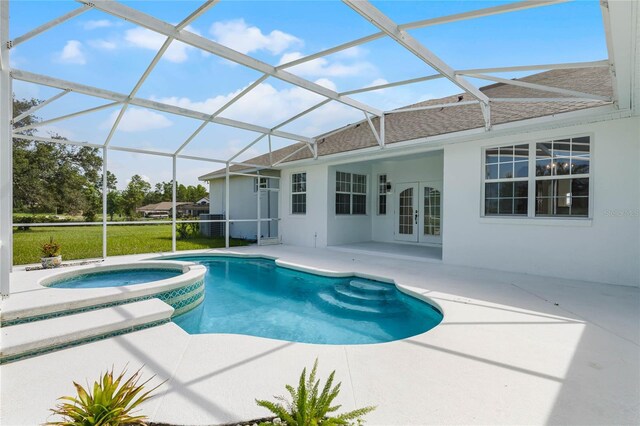 view of swimming pool with glass enclosure, a patio area, an in ground hot tub, and french doors