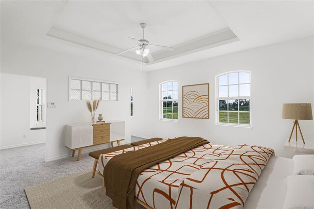 carpeted bedroom with ceiling fan and a tray ceiling