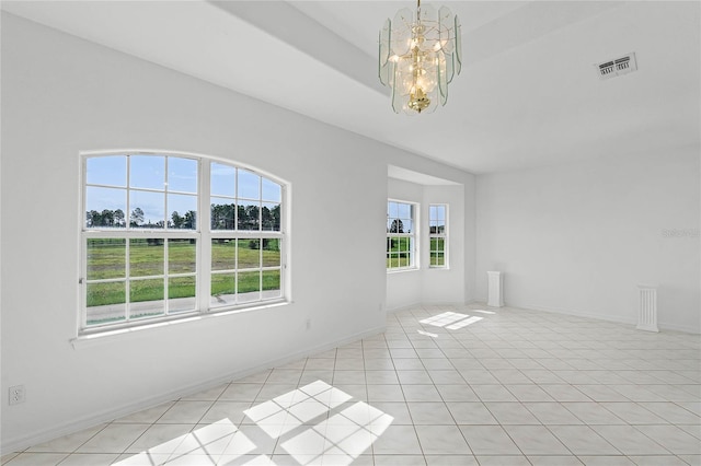 tiled empty room with an inviting chandelier