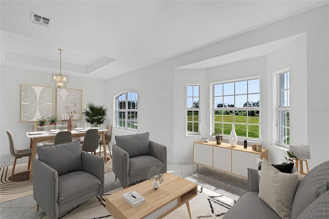 living room featuring a notable chandelier, a tray ceiling, a healthy amount of sunlight, and light tile patterned flooring