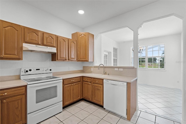 kitchen with light tile patterned flooring, white appliances, kitchen peninsula, and sink