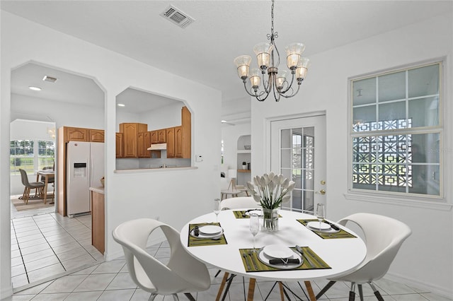 dining space with light tile patterned floors, a healthy amount of sunlight, and a notable chandelier