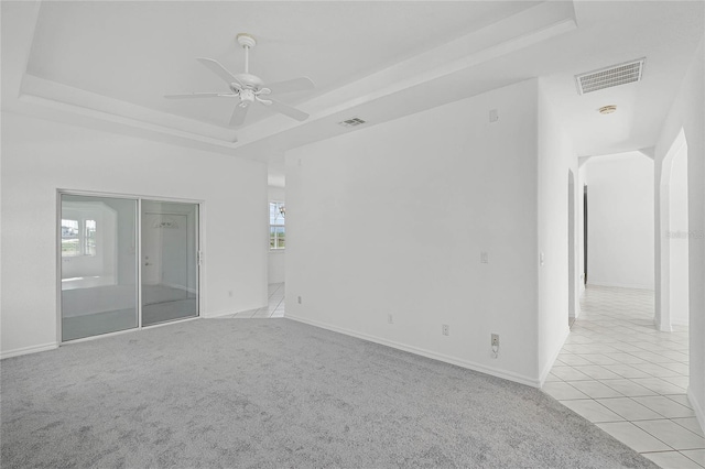 carpeted empty room featuring plenty of natural light, ceiling fan, and a tray ceiling