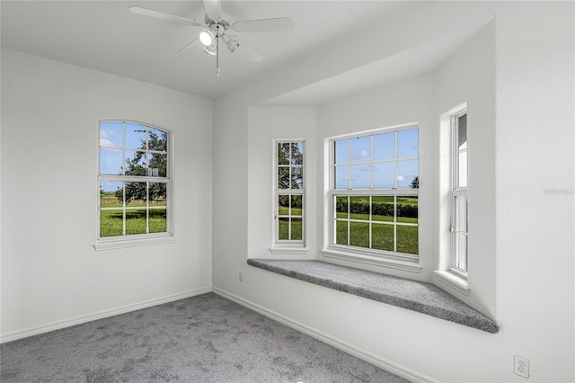 carpeted spare room featuring plenty of natural light and ceiling fan