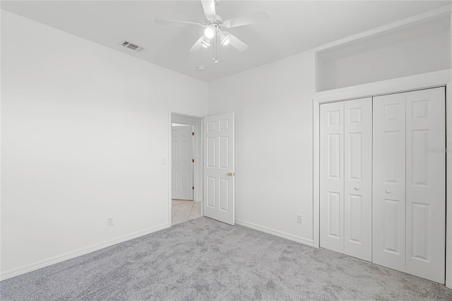 unfurnished bedroom with light carpet, a closet, and ceiling fan