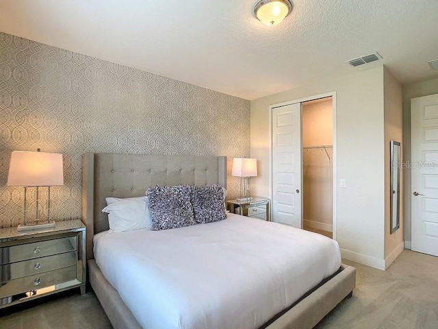 bedroom with a walk in closet, light carpet, and a closet