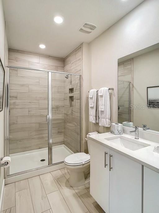 bathroom with walk in shower, vanity, and toilet