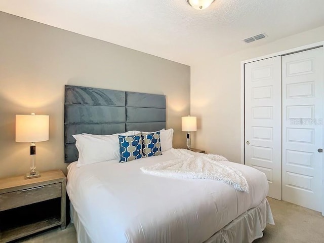 bedroom with light carpet, a textured ceiling, and a closet