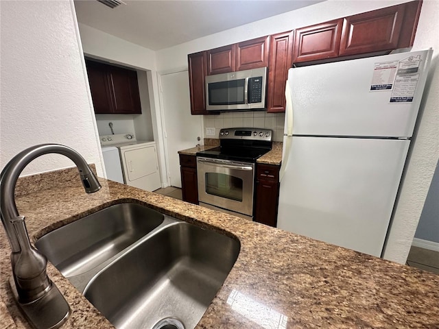 kitchen with separate washer and dryer, backsplash, appliances with stainless steel finishes, stone counters, and sink