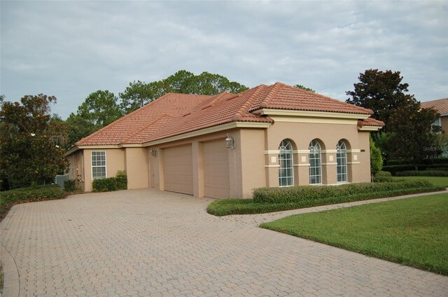 mediterranean / spanish-style home with a garage and a front lawn