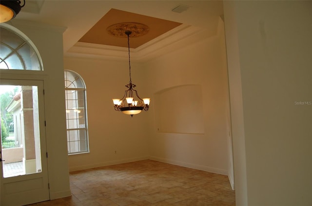 unfurnished dining area with crown molding, a tray ceiling, and a chandelier