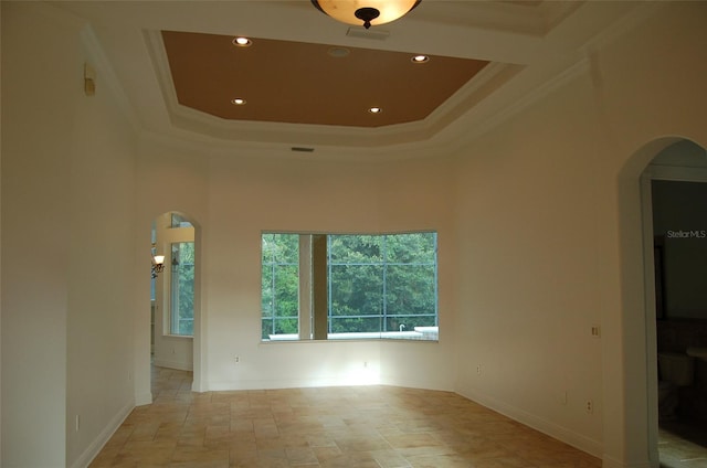 spare room with a raised ceiling, crown molding, and a towering ceiling