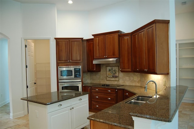 kitchen with sink, dark stone countertops, backsplash, stainless steel appliances, and white cabinets