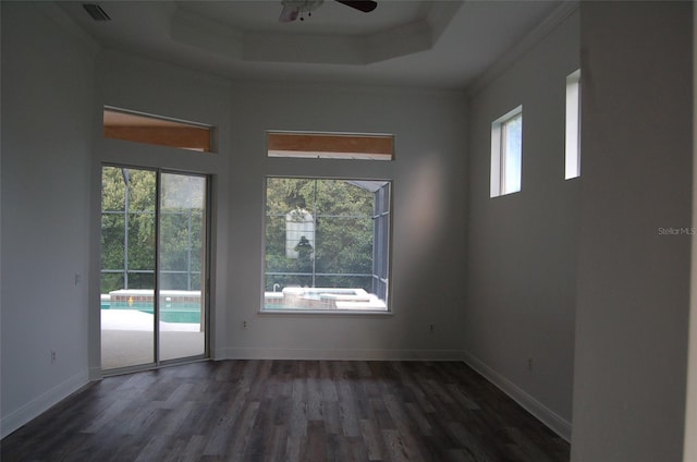 empty room featuring crown molding, dark wood-type flooring, ceiling fan, a towering ceiling, and a raised ceiling