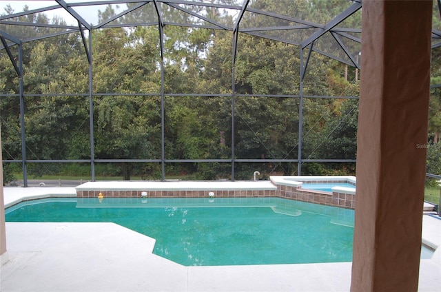 view of swimming pool with a patio area, an in ground hot tub, and glass enclosure