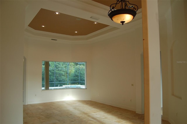 empty room featuring ornamental molding and a tray ceiling