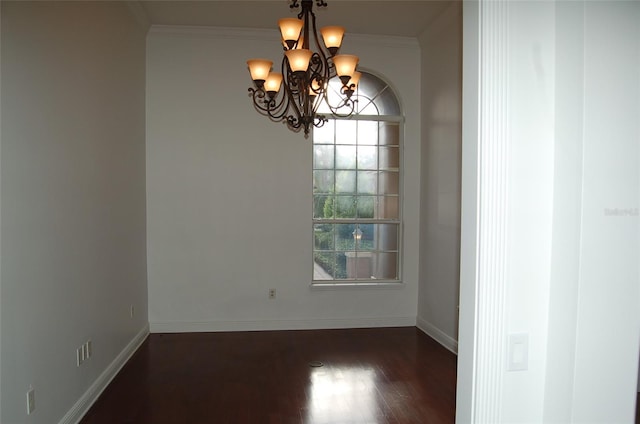 spare room with a notable chandelier, crown molding, and dark hardwood / wood-style floors