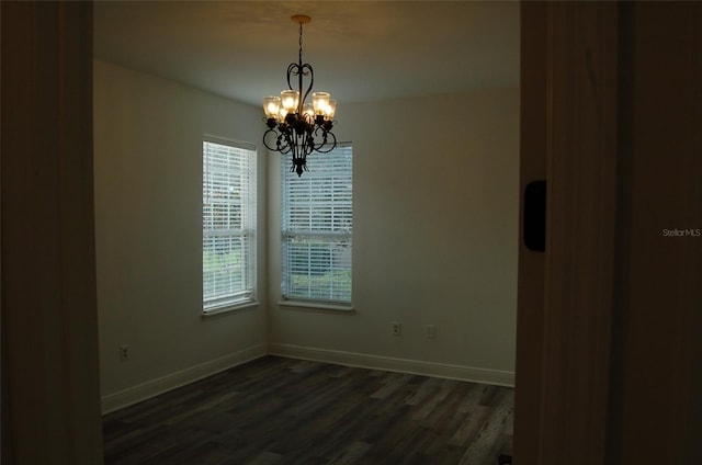 spare room with dark hardwood / wood-style flooring and a notable chandelier