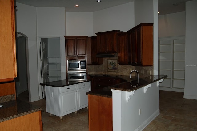 kitchen featuring sink, stainless steel appliances, a kitchen island, decorative backsplash, and kitchen peninsula