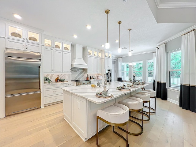 10193 Brocksport Cir, Gotha, FL 34734 - kitchen with built in fridge, custom range hood, white cabinetry, a large island, and light wood-style floors
