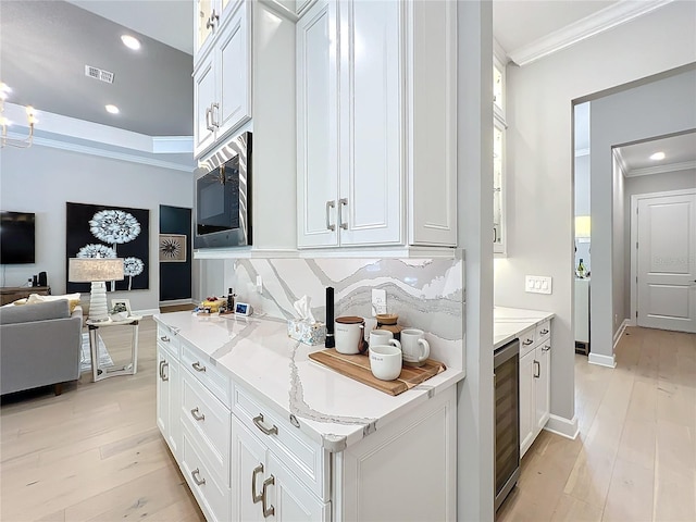 10193 Brocksport Cir, Gotha, FL 34734 - kitchen featuring crown molding, stainless steel microwave, white cabinets, tasteful backsplash, and light wood-style flooring