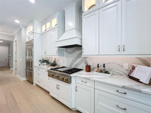 10193 Brocksport Cir, Gotha, FL 34734 - kitchen with custom exhaust hood, stainless steel appliances, ornamental molding, white cabinetry, and light stone counters