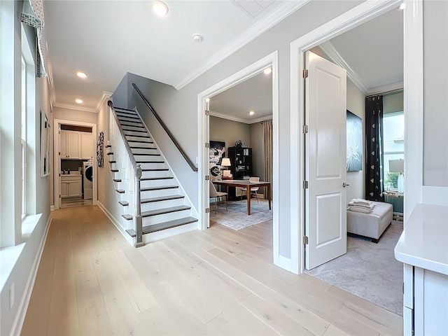 interior space with crown molding, washing machine and dryer, and hardwood / wood-style floors