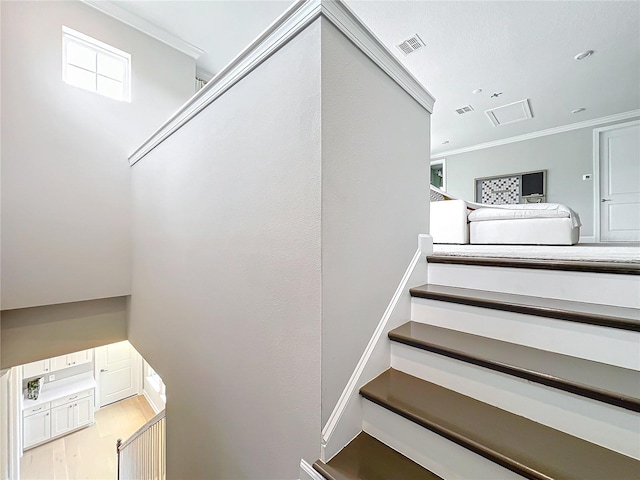 stairway featuring crown molding and wood-type flooring