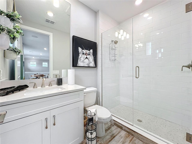 bathroom with vanity, hardwood / wood-style floors, a shower with shower door, and toilet