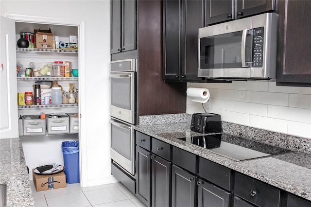 kitchen featuring light stone counters, stainless steel appliances, dark brown cabinets, and backsplash