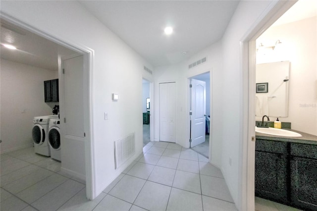 corridor with washer and dryer, sink, and light tile patterned floors