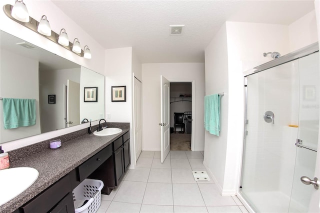 bathroom featuring tile patterned flooring, vanity, a shower with door, and a textured ceiling