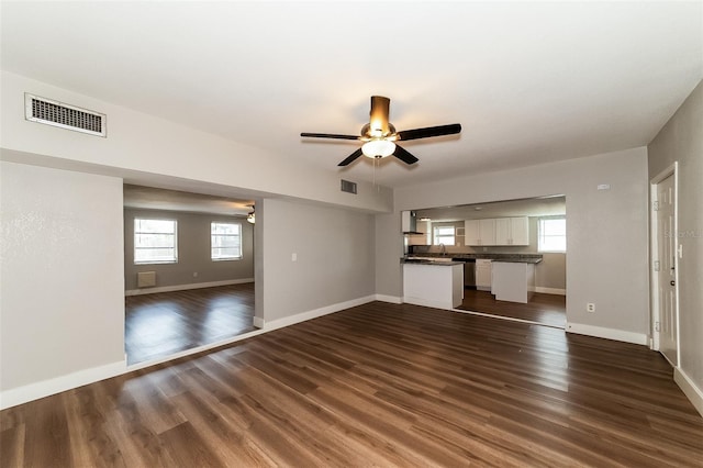 unfurnished living room featuring ceiling fan, dark hardwood / wood-style flooring, and a healthy amount of sunlight