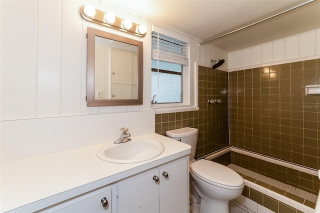 bathroom featuring toilet, tiled shower, a textured ceiling, and vanity