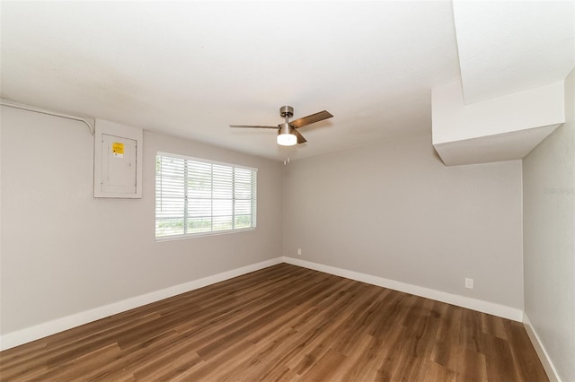 spare room with electric panel, ceiling fan, and dark hardwood / wood-style flooring