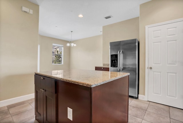 kitchen featuring stainless steel fridge, hanging light fixtures, a kitchen island, dark brown cabinetry, and light tile patterned flooring