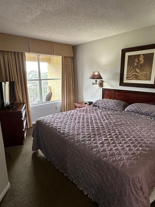 bedroom with dark colored carpet and a textured ceiling