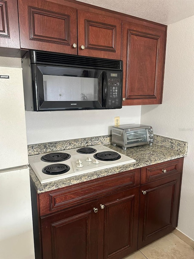 kitchen featuring light tile patterned flooring, white appliances, and light stone countertops