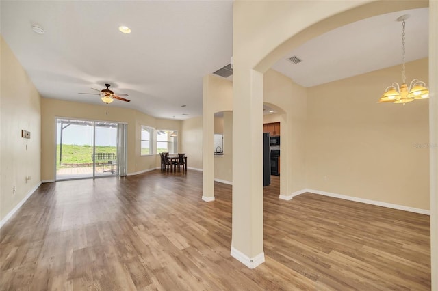 unfurnished living room with ceiling fan with notable chandelier and hardwood / wood-style floors