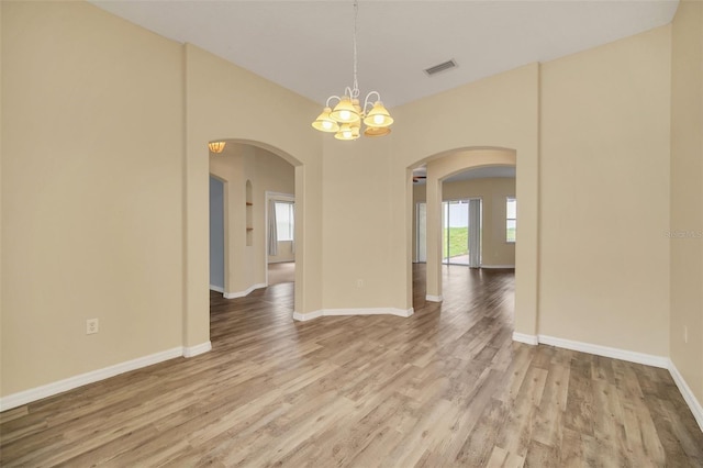 spare room with hardwood / wood-style flooring and an inviting chandelier