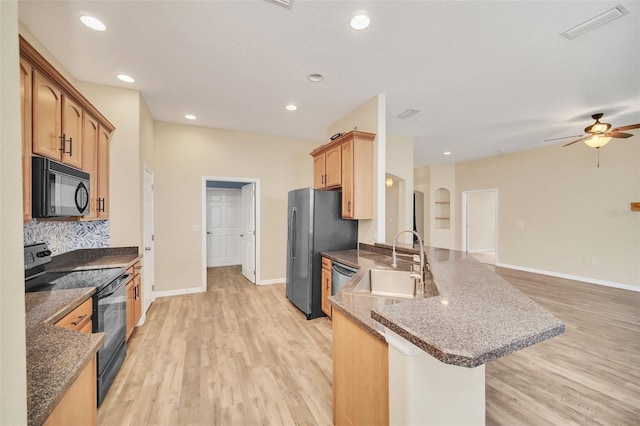 kitchen with light hardwood / wood-style floors, sink, black appliances, and kitchen peninsula