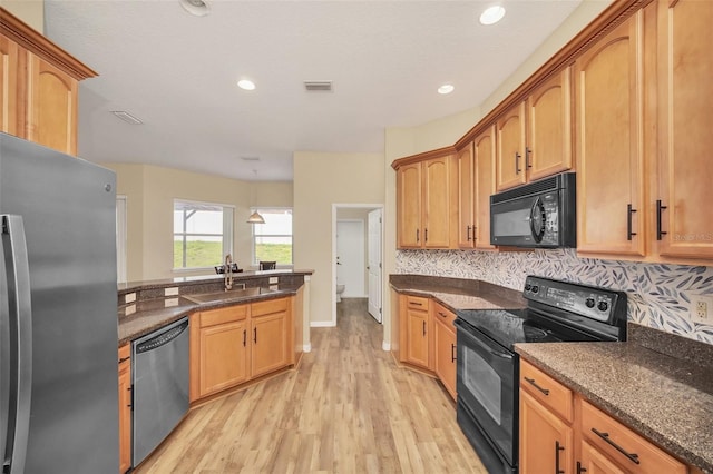 kitchen with sink, dark stone countertops, decorative backsplash, and black appliances