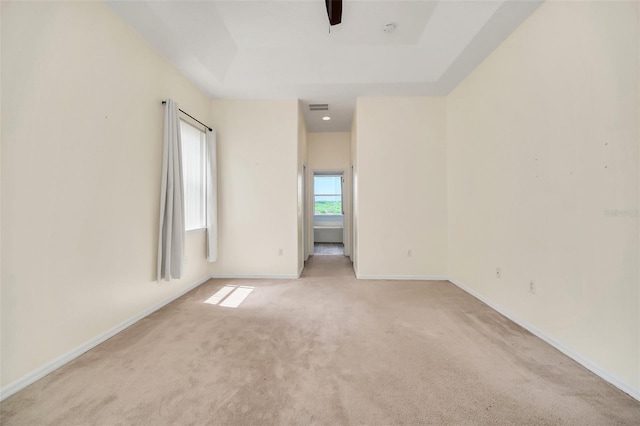 carpeted empty room featuring ceiling fan and a tray ceiling