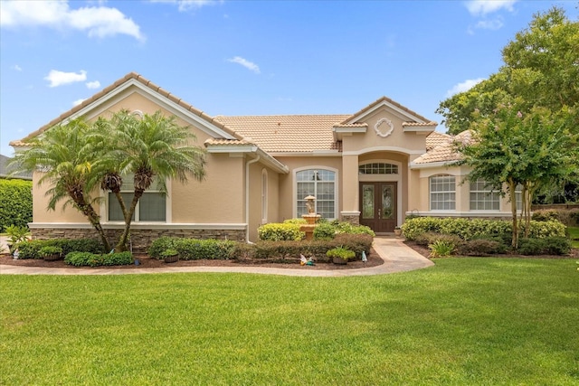 mediterranean / spanish house with a front yard and french doors