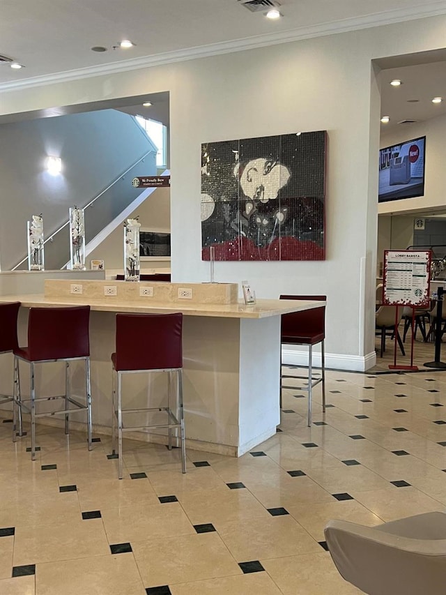 interior space featuring tile patterned floors, a kitchen bar, and crown molding