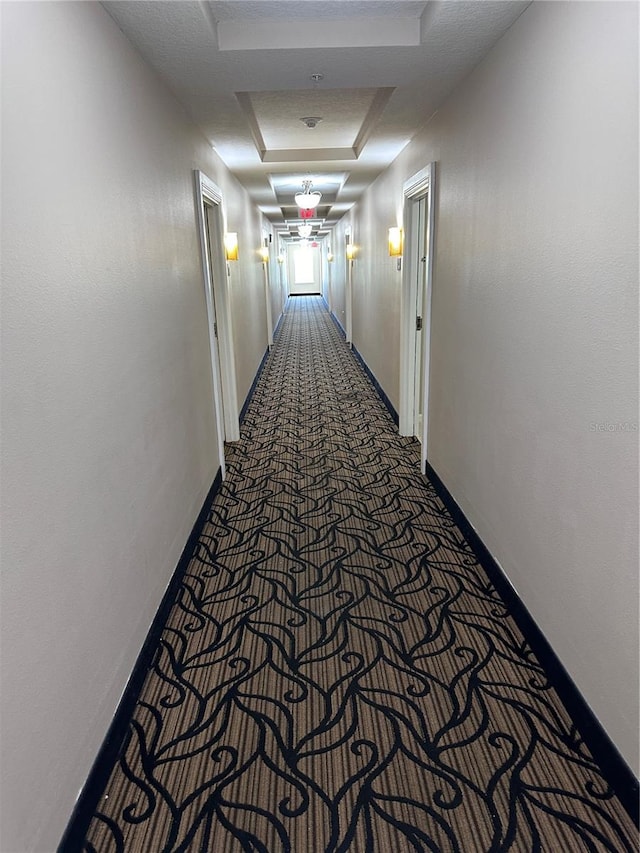 hallway with carpet and a tray ceiling