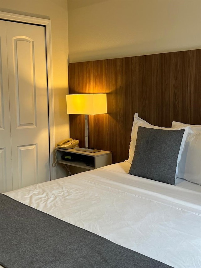 carpeted bedroom featuring wood walls and a closet