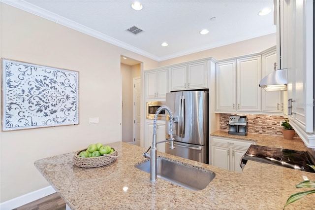 kitchen with sink, appliances with stainless steel finishes, white cabinetry, backsplash, and light stone counters